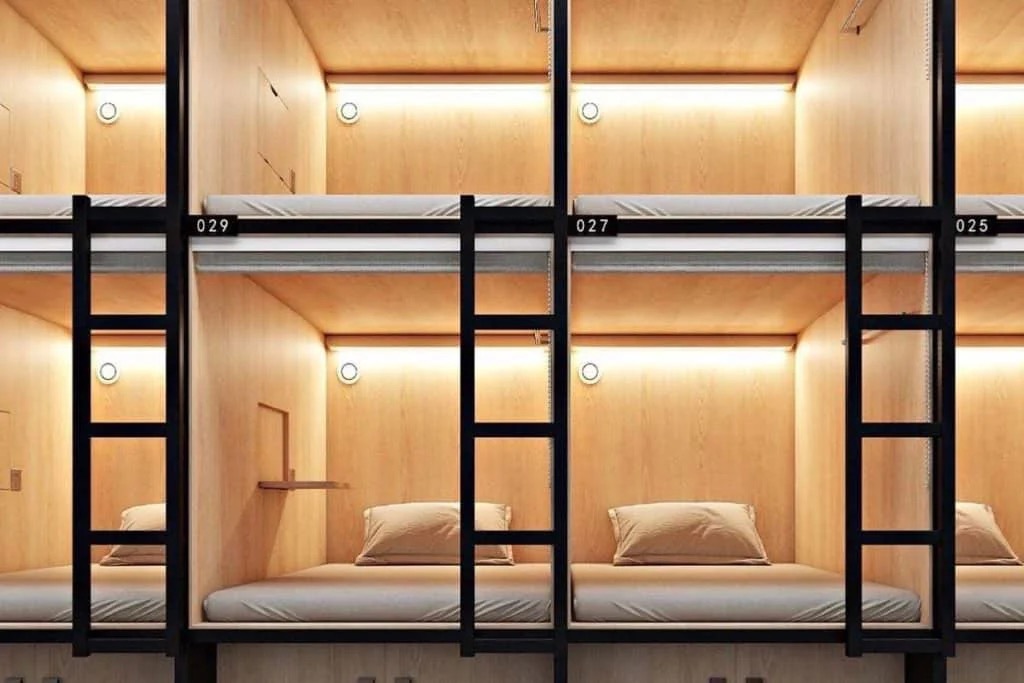 A corridor lined with stacked sleeping compartments, each opening lit from inside.