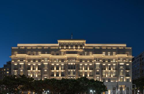 A long white hotel front with balconies, seen across a seafront avenue.